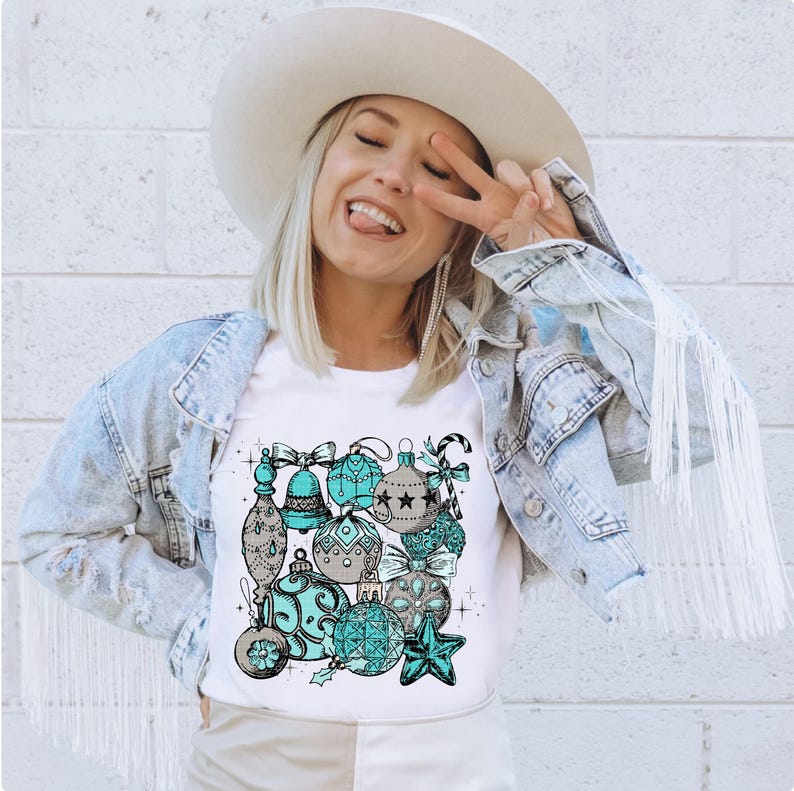 Peut inclure: Un t-shirt blanc avec un motif de boules de No&euml;l bleu sarcelle et grises. Les boules sont dispos&eacute;es en grappe et ont un style vintage.