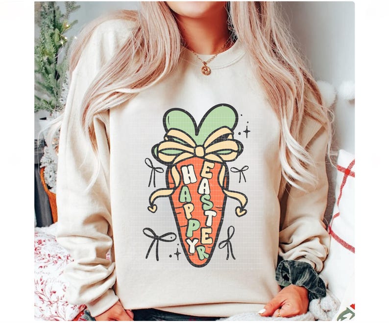 May include: A cream-colored sweatshirt with a cartoon carrot design. The carrot is decorated with a green bow and the words "Happy Easter" are written on the carrot.