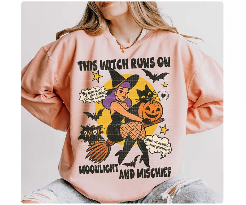 May include: A pale pink sweatshirt with a Halloween design. The graphic includes a witch on a broom, a black cat, and a pumpkin. The text on the sweatshirt says "THIS WITCH RUNS ON MOONLIGHT AND MISCHIEF."