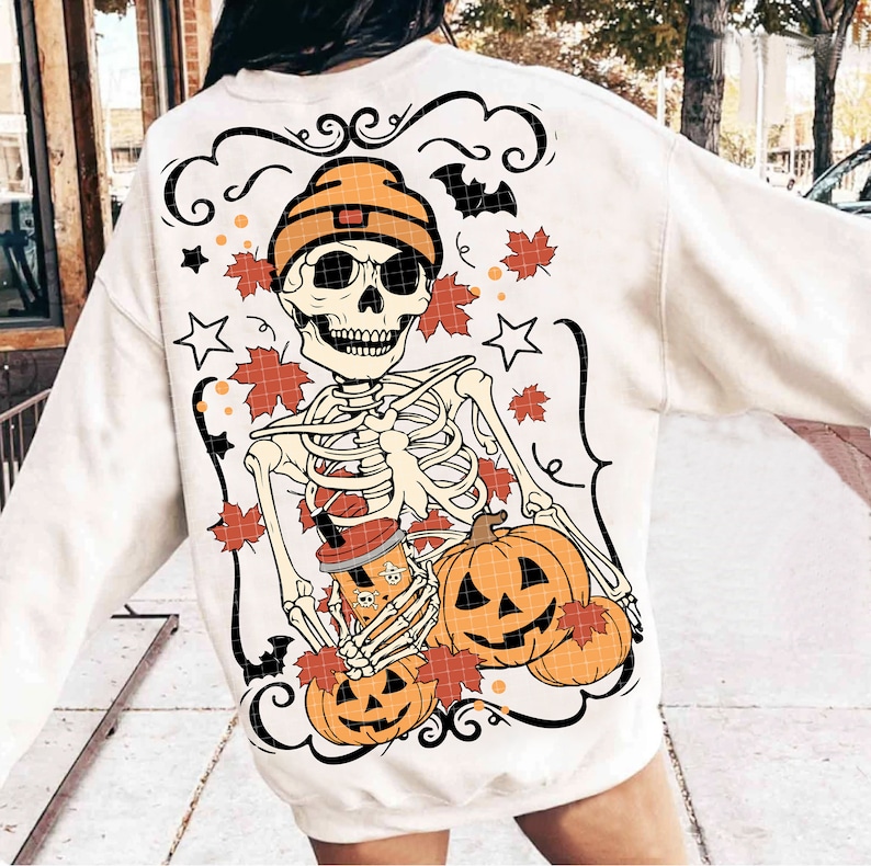 May include: White sweatshirt with a skeleton wearing a beanie holding a pumpkin and a cup of coffee. The design also includes fall leaves and stars.