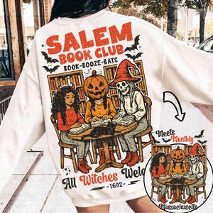 Może przedstawiać: Kremowa bluza z nadrukiem Salem Book Club. Projekt przedstawia trzy postacie, w tym głowę dyni i szkielet, czytające książki. Tekst zawiera "All Witches Welcomed - 1692".