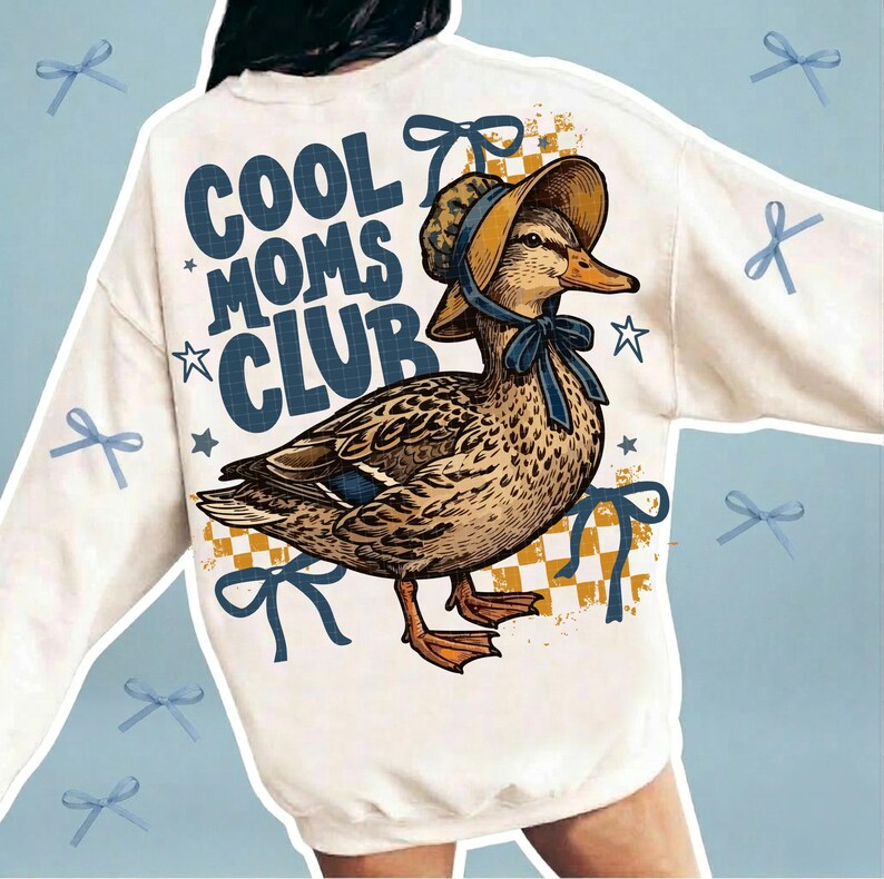 May include: Cream-colored sweatshirt with a graphic of a duck wearing a bonnet and the text "COOL MOMS CLUB" in navy blue. The duck is brown and tan with blue accents. Blue bows and stars are scattered around the design.