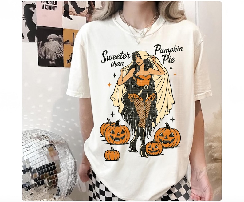 Peut inclure: T-shirt cr&egrave;me avec un motif sur le th&egrave;me d'Halloween. Le design pr&eacute;sente une femme costum&eacute;e, des citrouilles et le texte "Sweeter than Pumpkin Pie". Le t-shirt a une coupe ample.