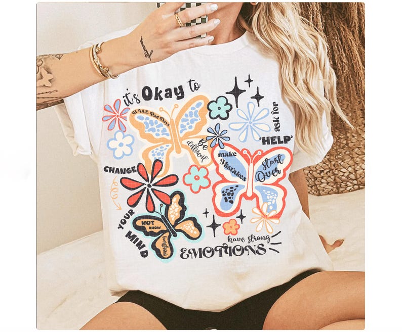 May include: White t-shirt with a colorful butterfly design and the text "It's Okay to Change Your Mind, Be Different, Make Mistakes, Ask for Help, Start Over, Have Strong Emotions".