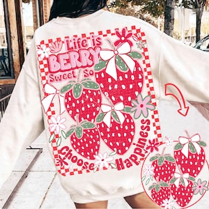 May include: White sweatshirt with a red and green strawberry graphic. The graphic says "Life is Berry Sweet So Choose Happiness".