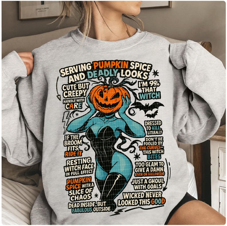 May include: A light gray sweatshirt with a Halloween-themed graphic. The graphic features a woman with a pumpkin head, surrounded by text that reads "Serving Pumpkin Spice and Deadly Looks." The design includes bats and witch-related phrases.
