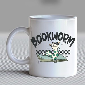 Pu&ograve; includere: Tazza in ceramica bianca con un'illustrazione di verme libro verde e nero e il testo "BOOKWORM" in nero. Il verme libro indossa gli occhiali e ha stelle sopra la testa.