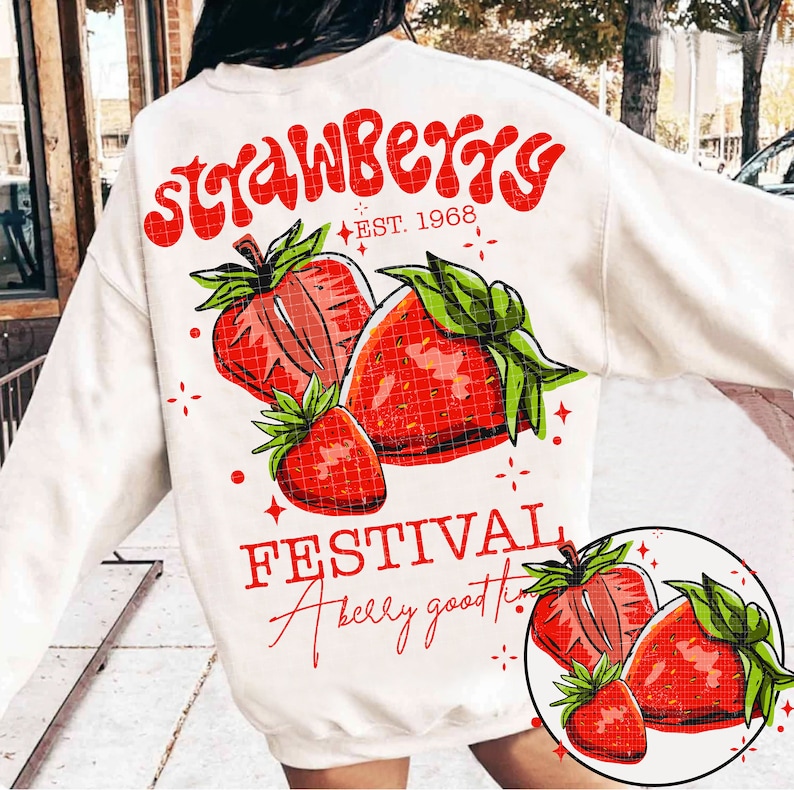 May include: White sweatshirt with a red and green strawberry graphic and the text "Strawberry Festival A belly good time" printed on the front.