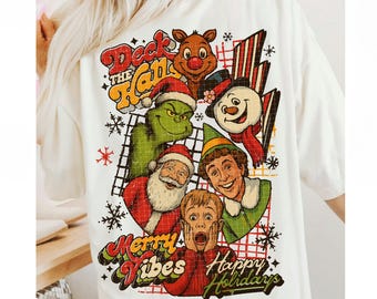 Könnte beinhalten: Weißes T-Shirt mit einem farbenfrohen Grafikdesign mit Weihnachtsfiguren wie dem Grinch, dem Weihnachtsmann und einem Schneemann. Der Text enthält "Deck the Halls", "Merry Vibes" und "Happy Holidays".