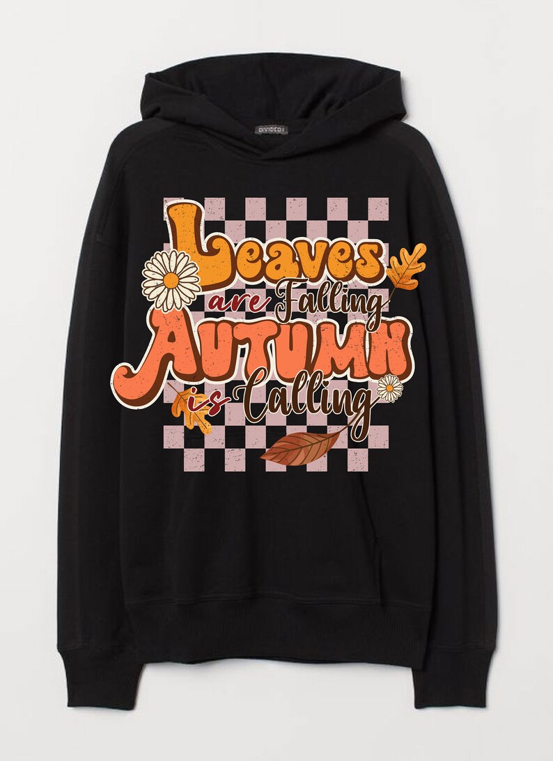 Op de afbeelding: Zwart hoodie met een grafische print van een geruit patroon, bladeren en de tekst "Leaves are falling, Autumn is calling".