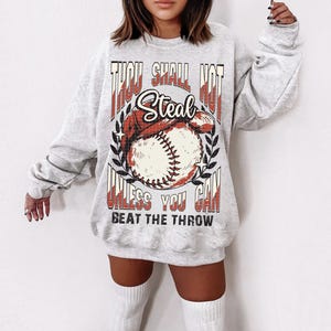 May include: Gray sweatshirt with a baseball graphic and the text "Thou Shall Not Steal Unless You Can Beat The Throw".