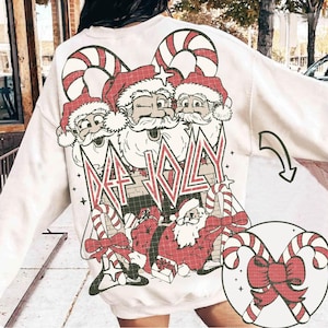 May include: White sweatshirt with a Christmas-themed graphic featuring three Santa Clauses with candy canes and the text "Def Jolly".