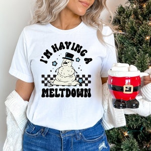 Pu&ograve; includere: Maglietta bianca con una grafica in bianco e nero di un pupazzo di neve che si scioglie. La grafica dice "I'm having a meltdown".