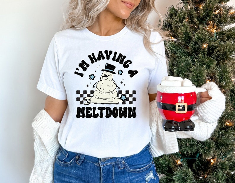 Pu&ograve; includere: Maglietta bianca con una grafica in bianco e nero di un pupazzo di neve che si scioglie. La grafica dice "I'm having a meltdown".
