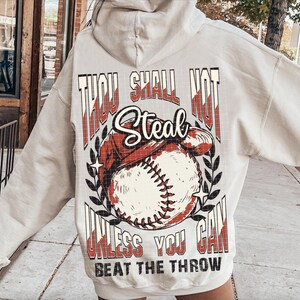 May include: A white hoodie with a baseball graphic and the text "Thou Shall Not Steal Unless You Can Beat The Throw".
