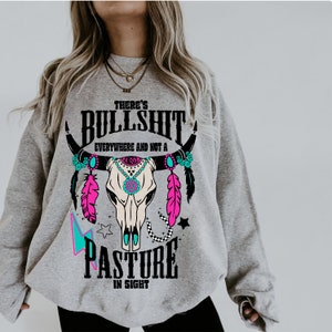 May include: Gray sweatshirt with a graphic of a skull with feathers and the text "There's Bullshit Everywhere and Not a Pasture in Sight".