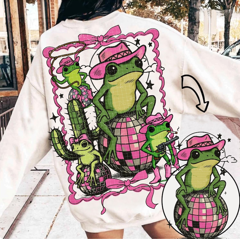 May include: White sweatshirt featuring a whimsical design of green frogs wearing pink cowboy hats, boots, and holding a lasso and a gun. The frogs are sitting on disco balls and a cactus, surrounded by a pink frame and bows.