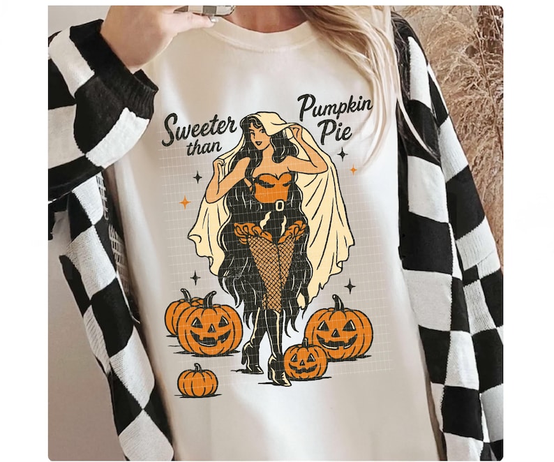 Peut inclure: Sweat-shirt blanc avec un motif d'Halloween repr&eacute;sentant une femme et des citrouilles. Le texte "Sweeter than Pumpkin Pie" est au-dessus du motif. La personne porte un cardigan &agrave; carreaux noir et blanc.