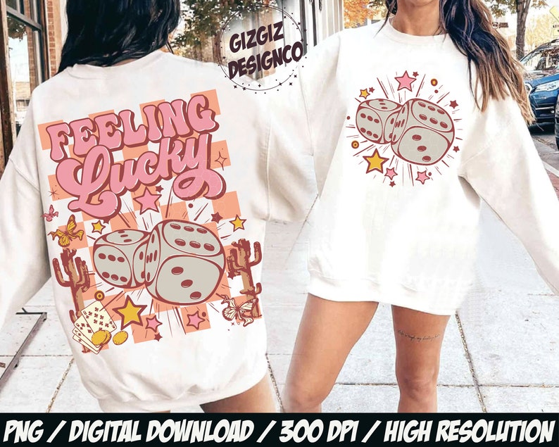 May include: Cream-colored sweatshirt with a graphic design featuring two dice, stars, and the text "Feeling Lucky" in pink and peach. The design includes cacti and butterflies. The sweatshirt is a digital download.