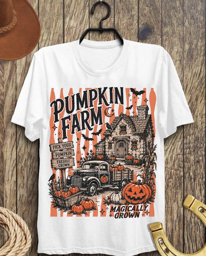 Peut inclure: Un t-shirt blanc avec une impression graphique repr&eacute;sentant une ferme de citrouilles. Le motif inclut un vieux camion, une maison en pierre, des citrouilles, des chauves-souris et un croissant de lune. Le texte indique PUMPKIN FARM, PICK YOUR PUMPKIN FRESHLY GROWN et MAGICALLY GROWN.