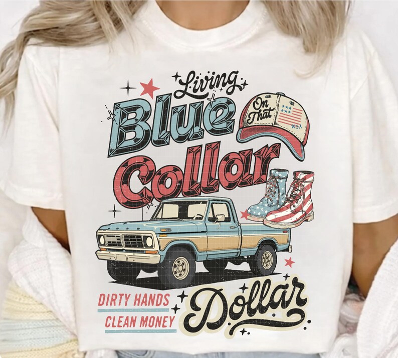 May include: White t-shirt with a graphic design featuring a blue and red vintage truck, boots, and a baseball cap. The text reads "Living Blue Collar Dollar" with additional text "Dirty Hands Clean Money".