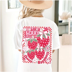 May include: White t-shirt with a red, pink, and green graphic print of strawberries and flowers. The graphic says "Life is Berry Sweet So Choose Happiness".