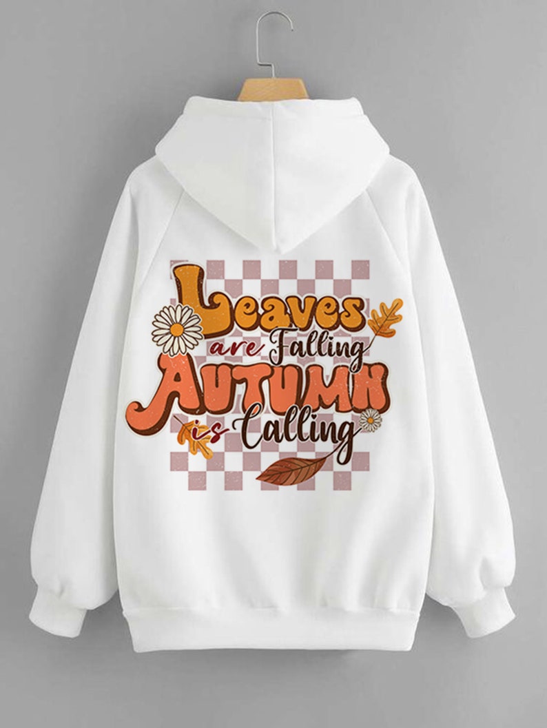 Op de afbeelding: Witte hoodie met een grafische print op de rug. De print heeft een geruite achtergrond met bladeren, bloemen en de tekst "Leaves are Falling Autumn is Calling".