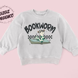 Pu&ograve; includere: Una felpa grigia chiaro con una grafica di un verme che indossa gli occhiali e legge un libro. Il testo "BOOKWORM" &egrave; sopra il verme.