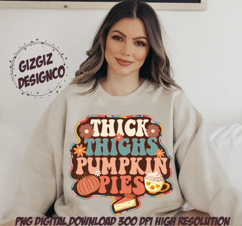 May include: A beige sweatshirt with a retro-style graphic design that says "Thick Thighs Pumpkin Pies". The graphic features a pumpkin, a cup of coffee, and a slice of pie.