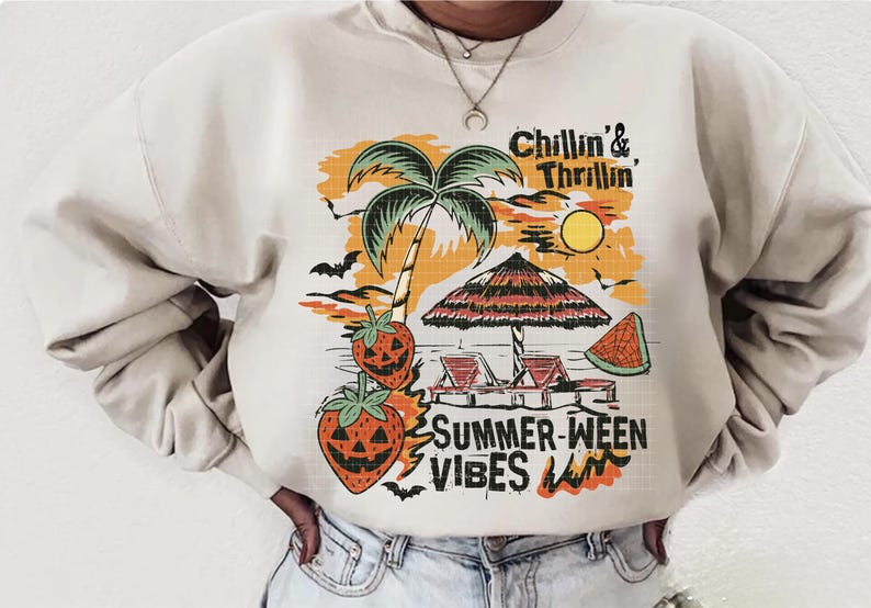 May include: Cream-colored sweatshirt with a graphic design featuring a palm tree, beach umbrella, and jack-o'-lantern strawberries. The text reads "Chillin' & Thrillin' SUMMER-WEEN VIBES". The design has orange, black, and green accents.
