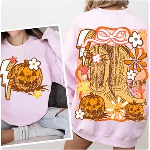 May include: A light pink sweatshirt featuring a pumpkin graphic with a lightning bolt and flower. The back of the sweatshirt has a design with cowboy boots, pumpkins, flowers, and the text "Fall Vibes".