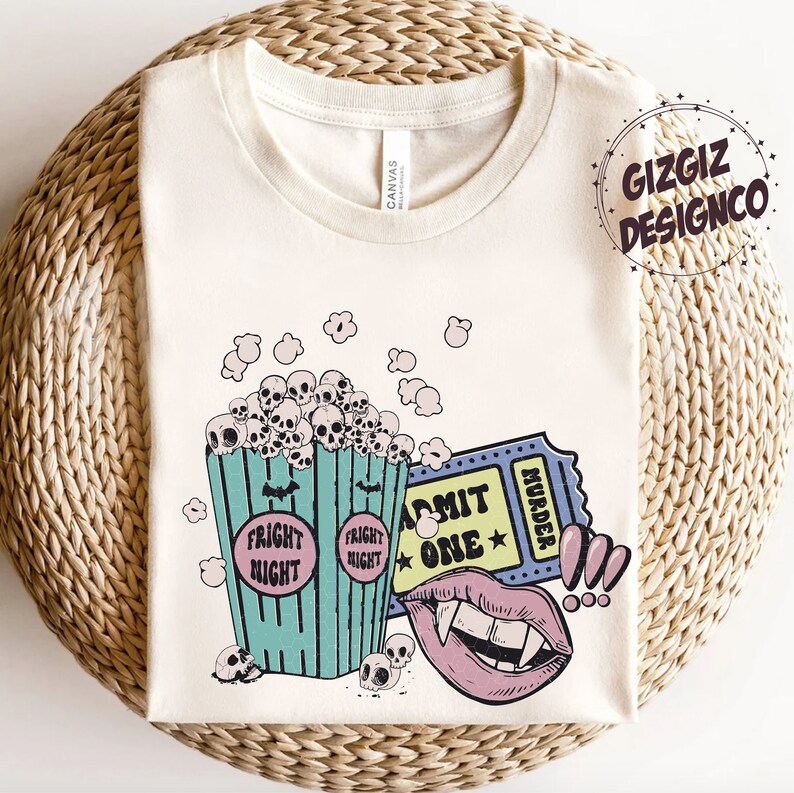 May include: A white t-shirt with a graphic design of a bucket of popcorn with skulls, a movie ticket that says "Admit One" and "Murder", and a vampire mouth with fangs. The popcorn bucket says "Fright Night" on both sides.