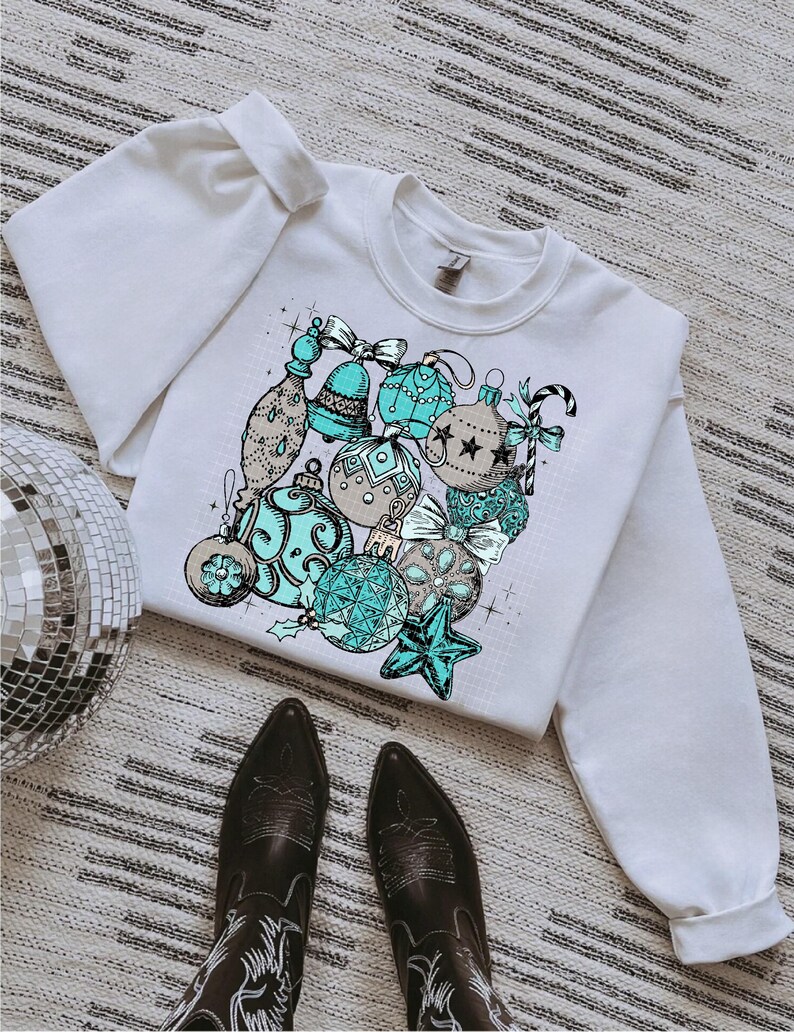 Peut inclure: Sweat-shirt blanc avec un motif d'ornements de No&euml;l bleus et bruns. Les ornements sont dessin&eacute;s dans un style vintage.