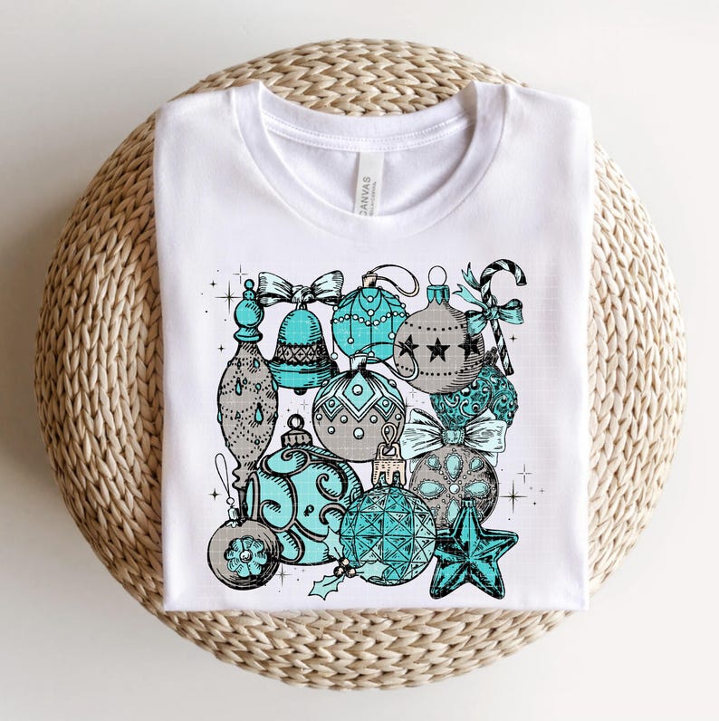 Peut inclure: T-shirt blanc avec un motif d'ornements de No&euml;l bleu sarcelle et gris. Les ornements sont d&eacute;cor&eacute;s d'&eacute;toiles, de volutes et d'autres d&eacute;tails festifs.