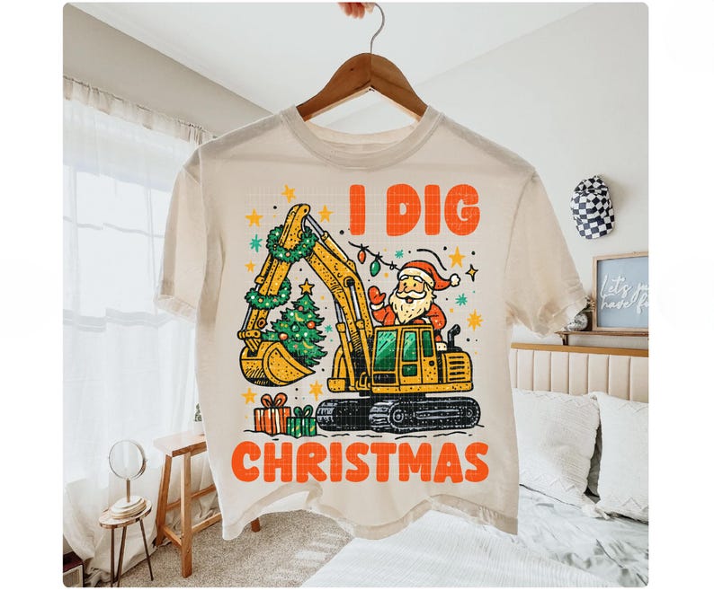 May include: Cream-colored t-shirt featuring a yellow excavator with a Christmas tree in its bucket and Santa Claus in the driver's seat. The text "I DIG CHRISTMAS" is printed in orange.