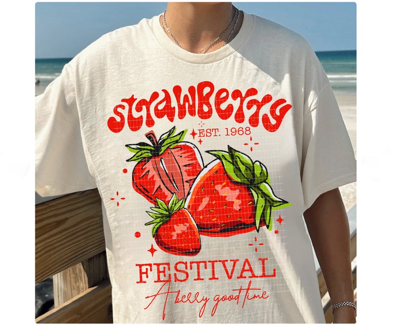 May include: White t-shirt with a red and green strawberry graphic and the text "Strawberry Festival" and "A really good time" in red.