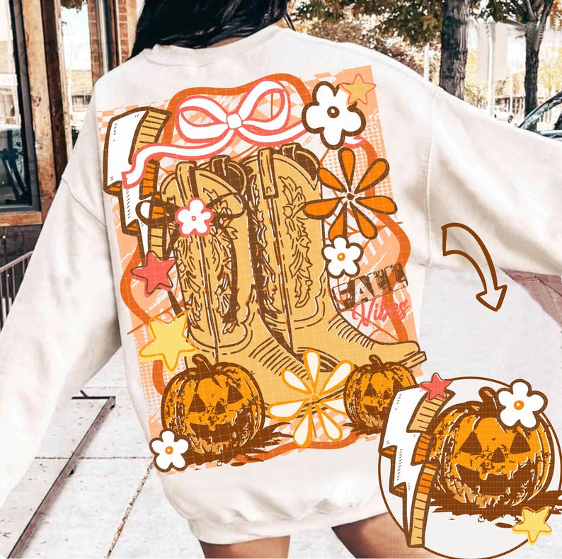 May include: Cream-colored sweatshirt featuring a fall-themed graphic. The design includes cowboy boots, jack-o'-lanterns, flowers, stars, and the text "Fall Vibes" in orange and brown hues. A bow and lightning bolt complete the design.