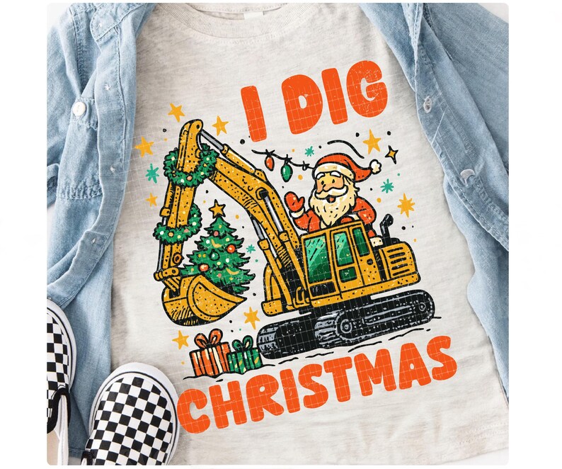 May include: A light gray t-shirt with the text "I DIG CHRISTMAS" in orange. The graphic features a yellow excavator with Santa Claus in the driver's seat, a Christmas tree, and wrapped gifts. The excavator has a green wreath and string lights.