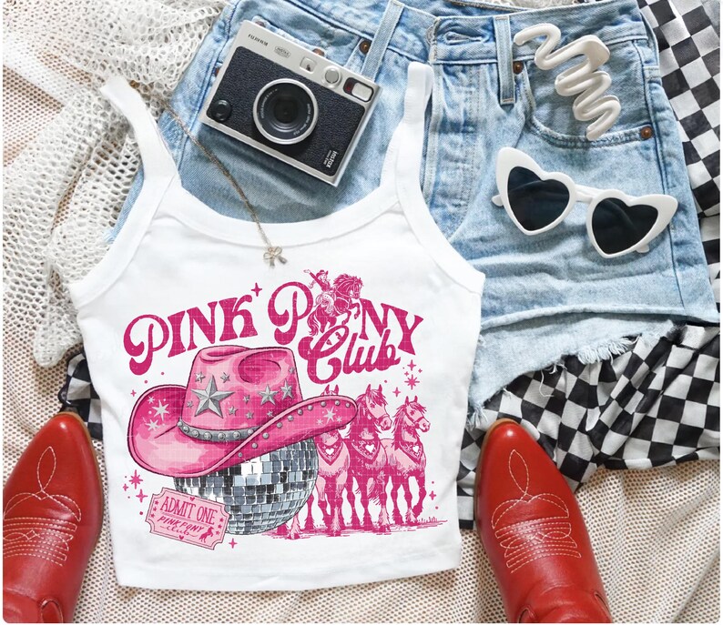 May include: White tank top with a pink graphic that reads "PINK PONY CLUB" featuring a pink cowboy hat, disco ball, and horses. The image also includes red cowboy boots, denim shorts, a camera, and heart-shaped sunglasses.