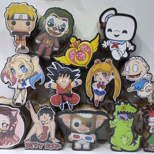 Può includere: Una collezione di ritagli di personaggi colorati, tra cui Naruto, il Joker e Sailor Moon. Altri personaggi includono Harley Quinn, Goku e Reptar. La parola "Cajitax" è scritta verticalmente sul lato sinistro.