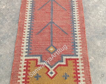 May include: A long, narrow red and blue rug with a geometric pattern. The rug has a fringe on both ends and is made of a woven material.