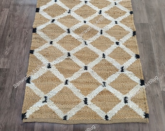 May include: A natural fiber rug with a diamond pattern in white and black on a beige background. The rug is made of jute and is perfect for adding a touch of natural texture to any room.