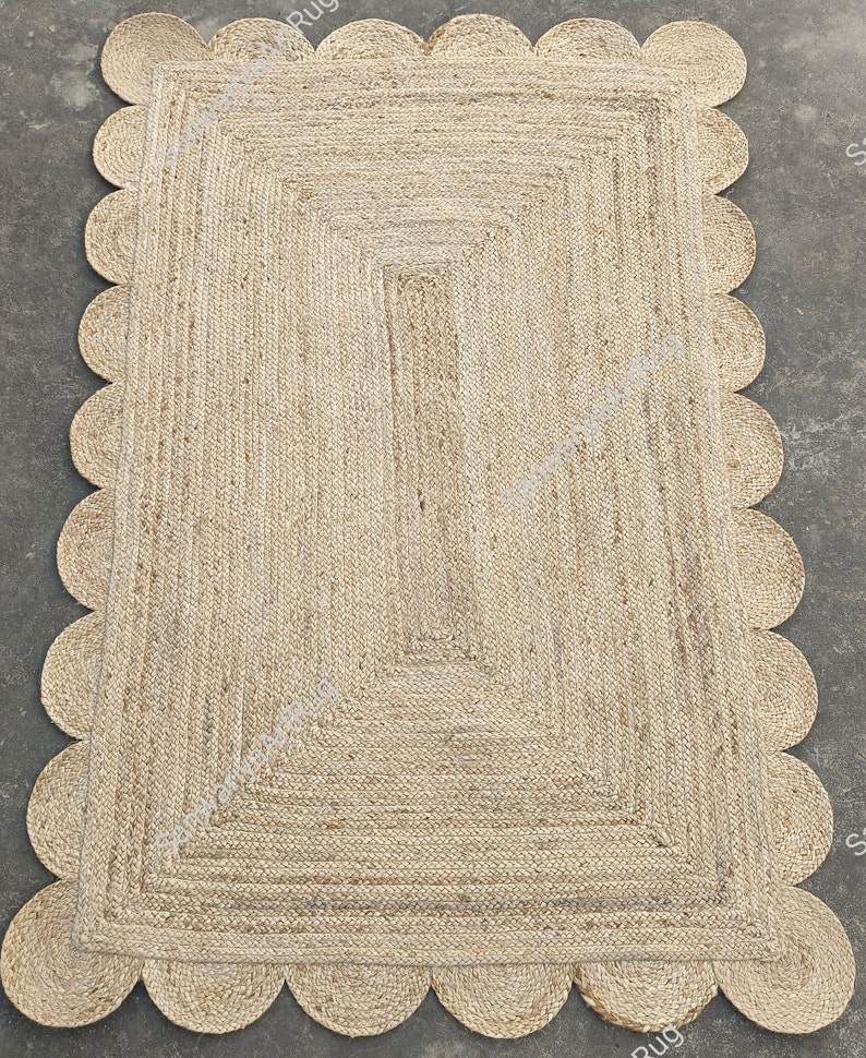 May include: A natural fiber rug with a scalloped edge. The rug is made of woven jute and has a light brown color.