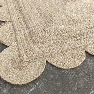 May include: A natural fiber rug with a scalloped edge. The rug is made of woven jute and has a light beige color.
