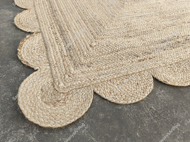 May include: A natural fiber rug with a scalloped edge. The rug is made of woven jute and has a light beige color.