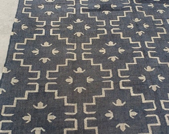 May include: A black and white rug with a geometric pattern. The rug has a fringe border and is made of a woven material.