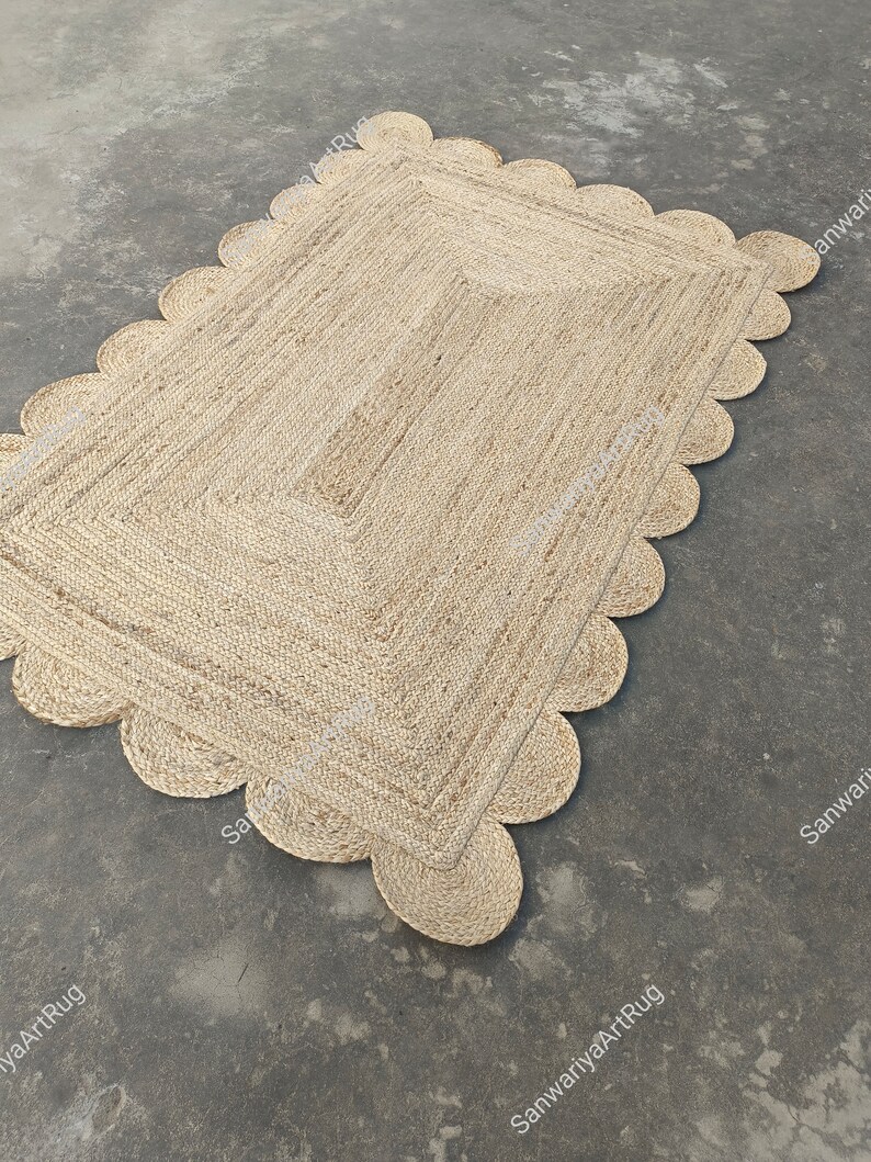 May include: A natural fiber rug with a scalloped edge. The rug is made of jute and has a light brown color.