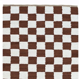 Peut inclure: Un tapis à carreaux bruns et blancs avec une texture tissée.