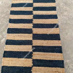 May include: A striped jute rug with alternating black and natural jute stripes. The rug is woven with a simple, traditional design.