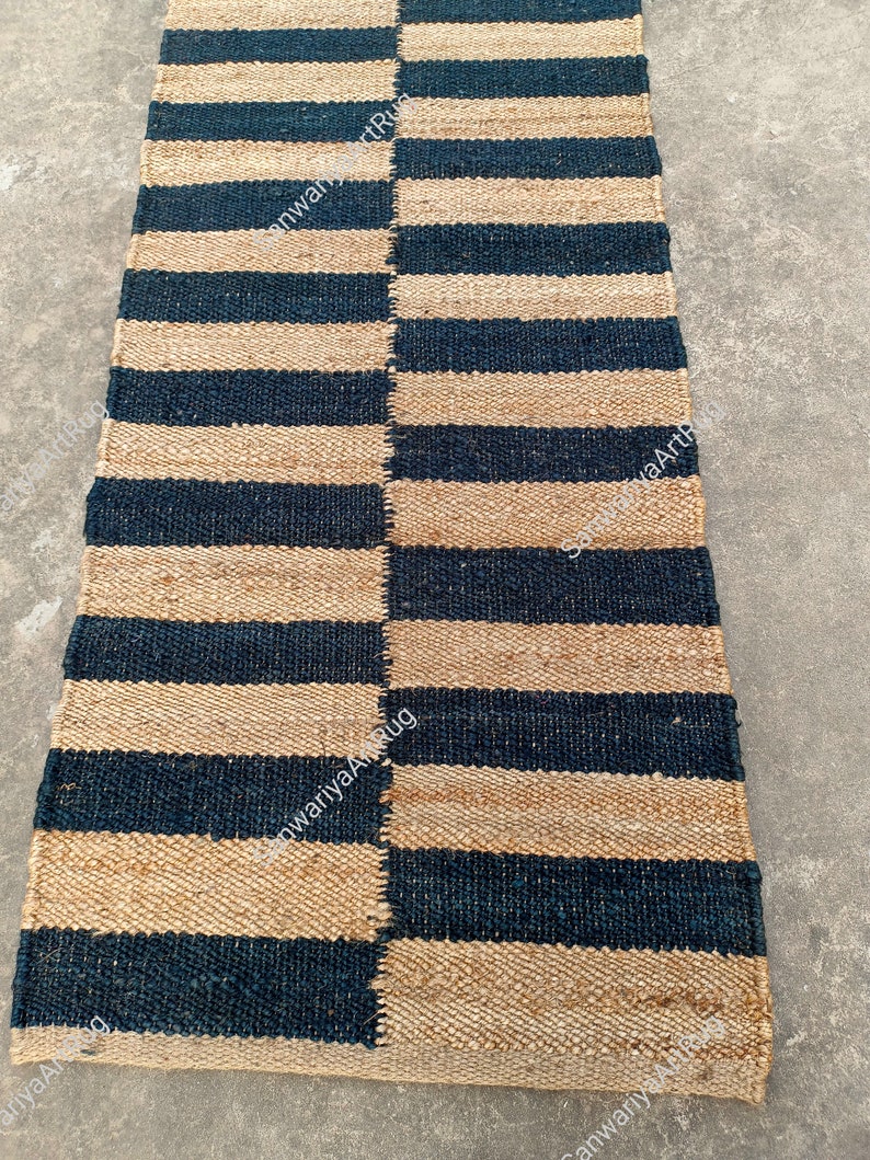 May include: A striped jute rug with alternating black and natural jute stripes. The rug is woven with a simple, traditional design.